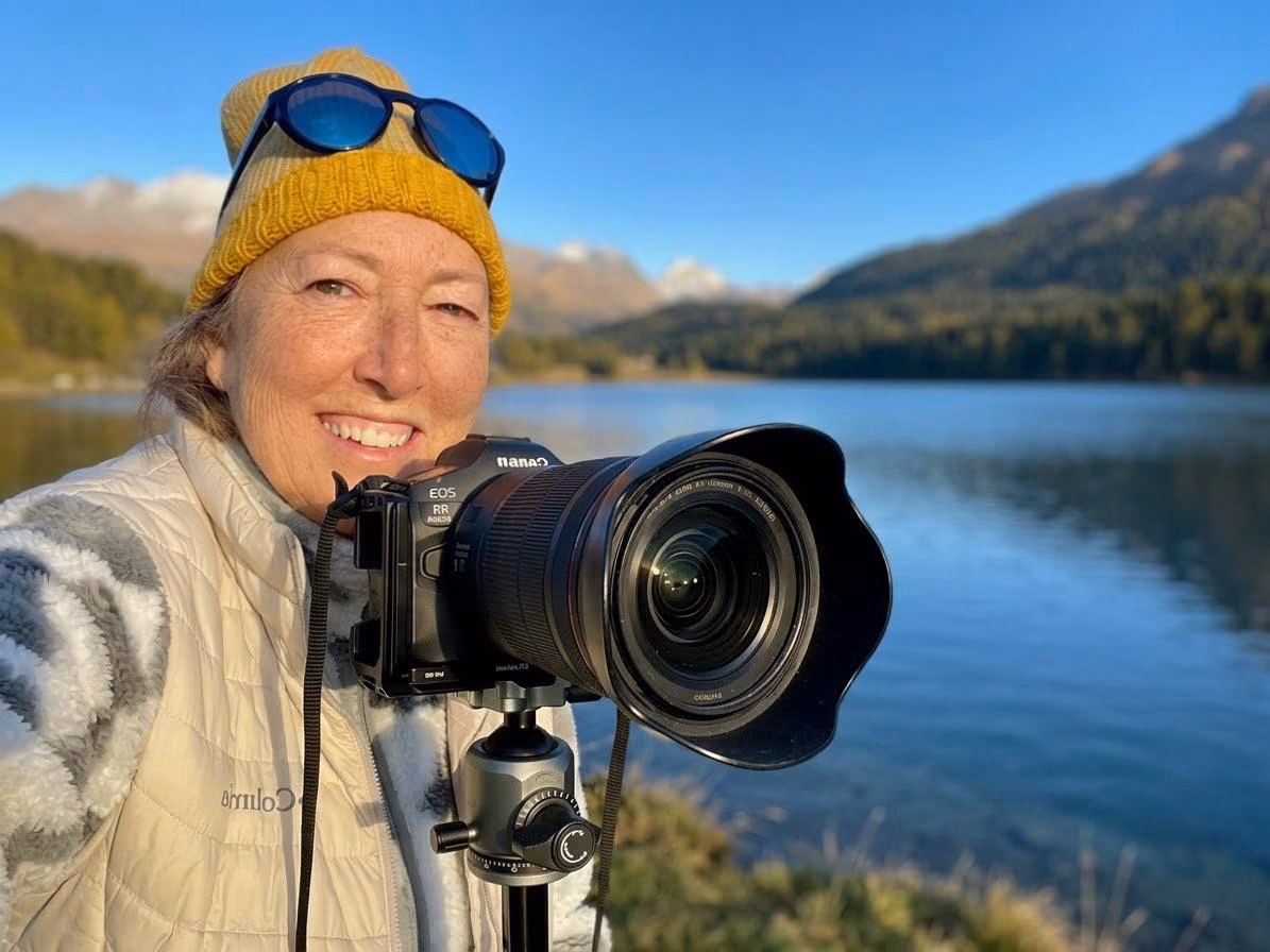 Janet lächelt neben ihrer Canon-Kamera am See